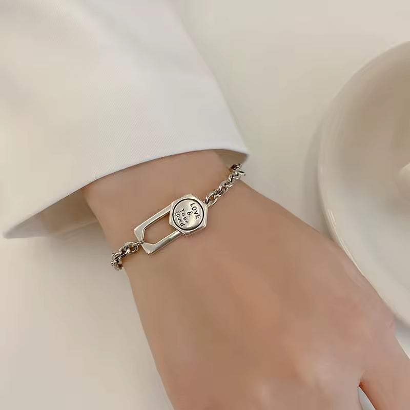 Silver bracelet on a wrist with a plain background