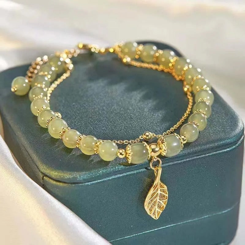 Beaded bracelet with a gold leaf charm on a teal jewelry box