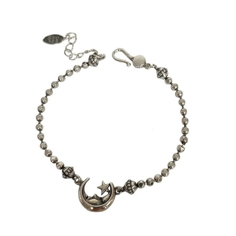 Silver bracelet with moon and star charm on a white background