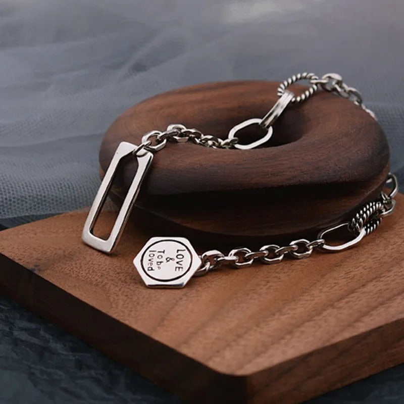 Silver bracelet with a hexagonal tag on a wooden surface