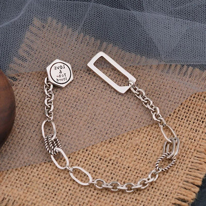Silver chain bracelet with a clasp on a textured fabric background