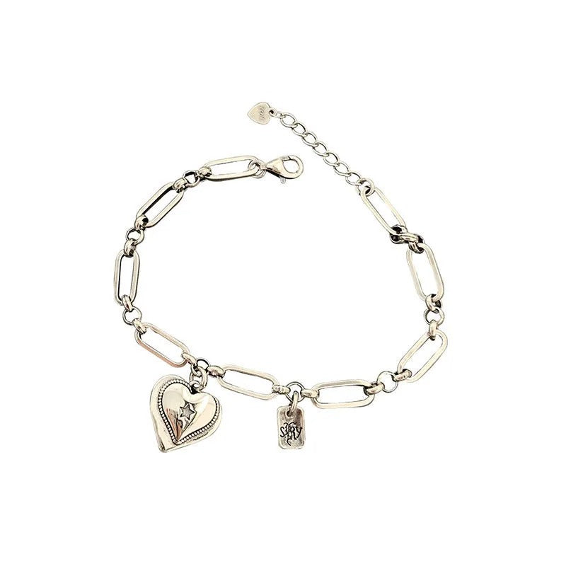 Silver bracelet with heart-shaped charm and tag on a white background