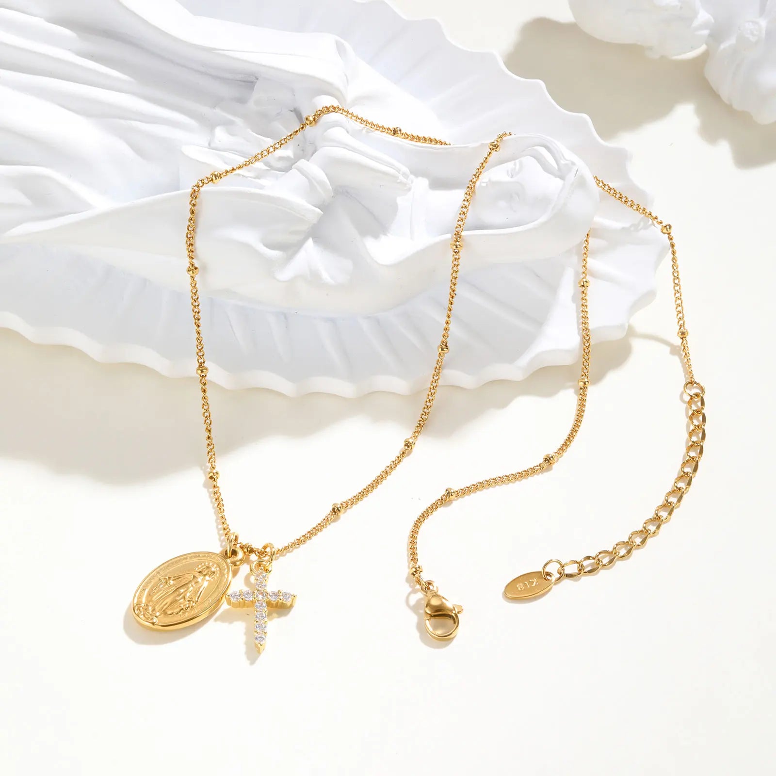 Gold necklace with religious charms on a white fabric background
