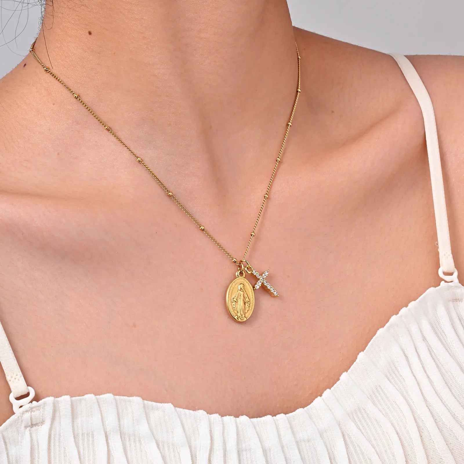 Gold necklace with a pendant on a person wearing a white top