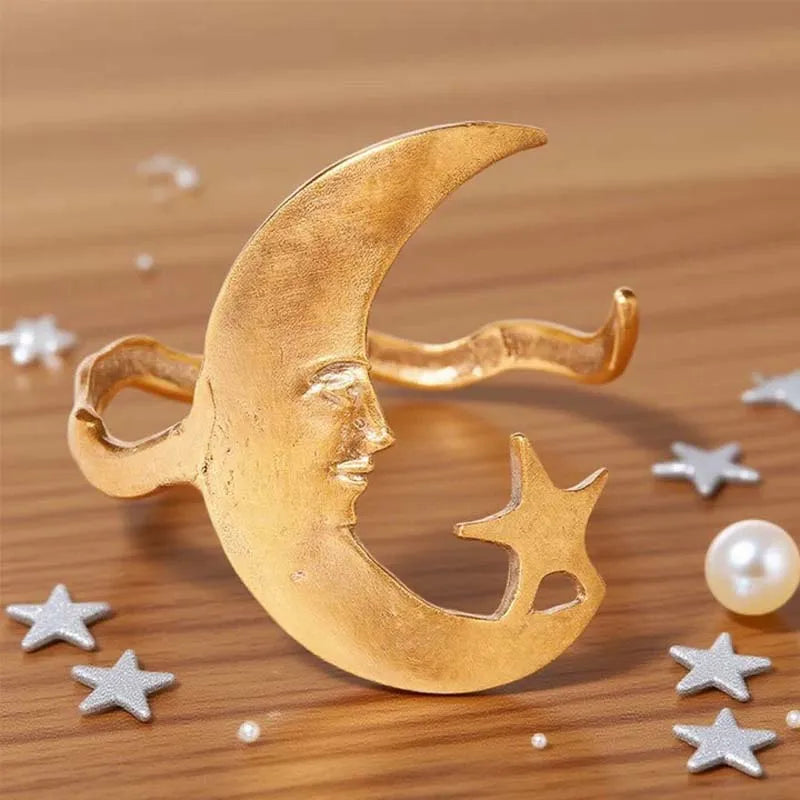 Gold moon and star brooch on a wooden surface with decorative stars and pearls.