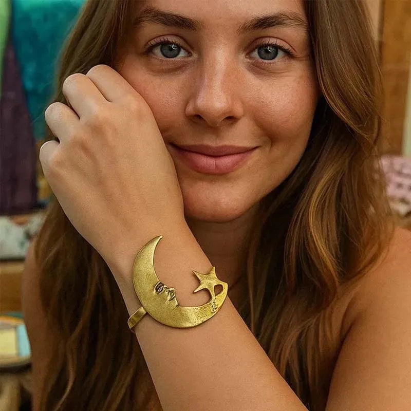 Woman wearing a gold bracelet with a moon and star design.