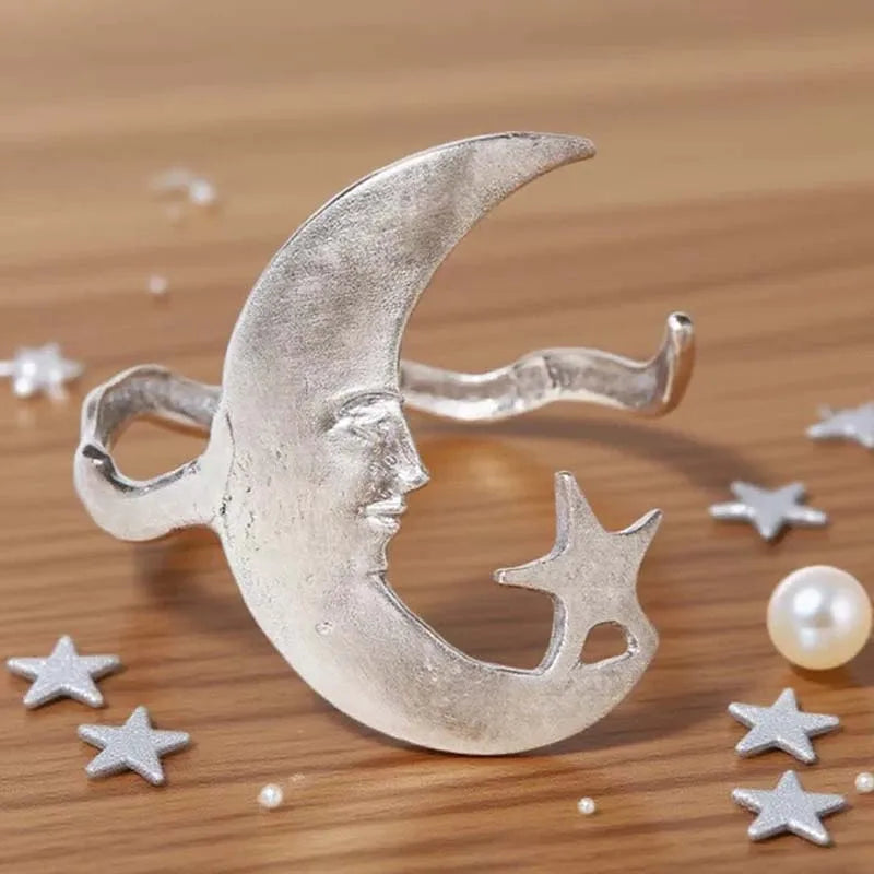 Silver moon and star design on a wooden surface with pearls