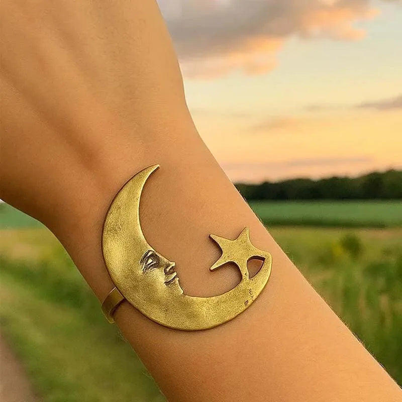 Gold crescent moon and star bracelet on a wrist with a scenic background