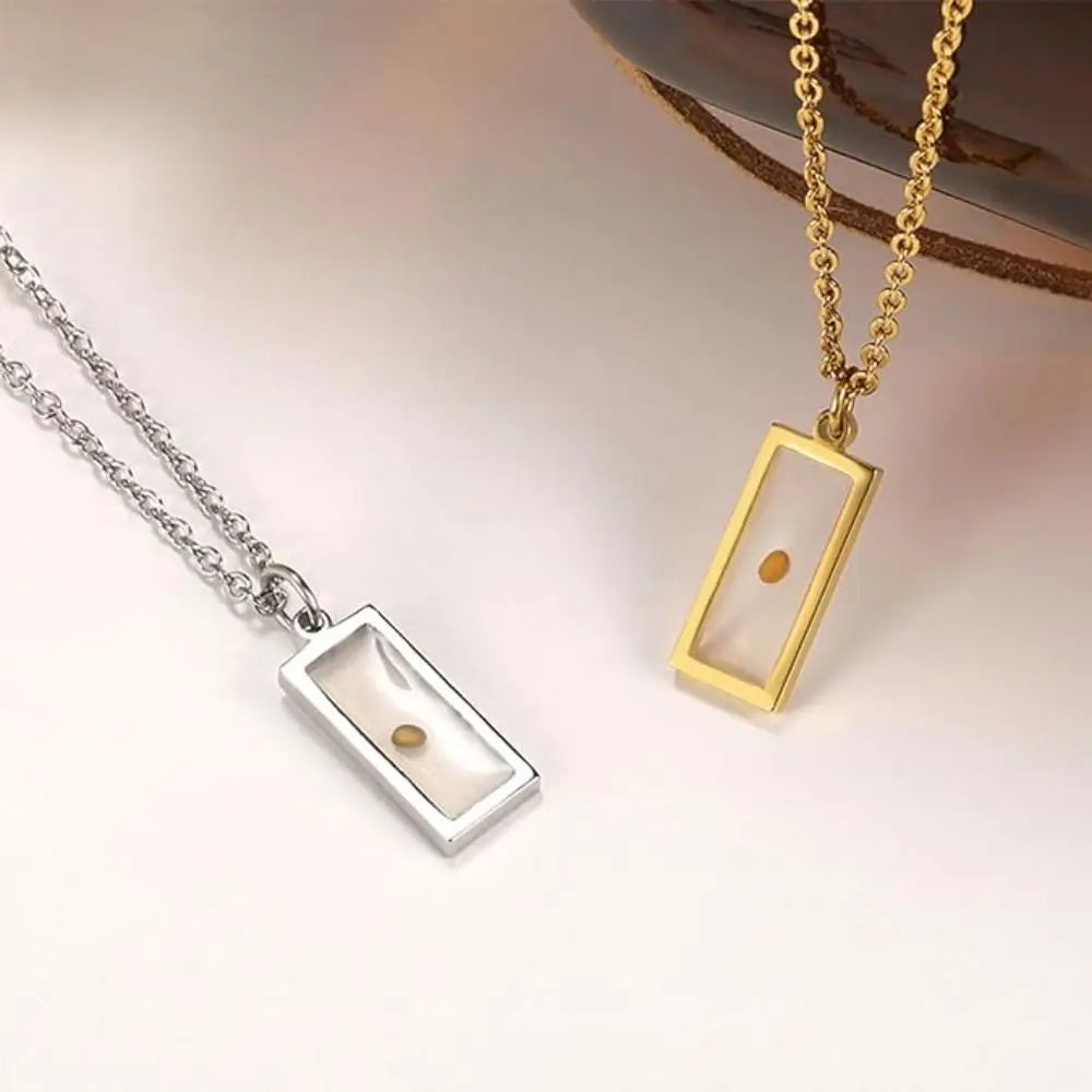 Two necklaces with rectangular pendants on a soft background