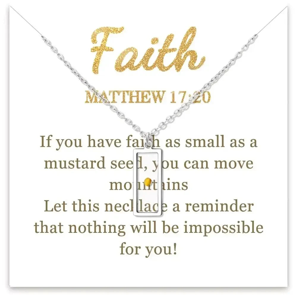 A silver necklace with a small rectangular pendant featuring a gold dot in the center, displayed on a white card with gold and brown text. The card includes the word 'Faith' and a Bible verse from Matthew 17:20.