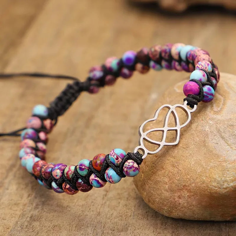 Multicolored beaded bracelet with a silver infinity charm on a wooden surface
