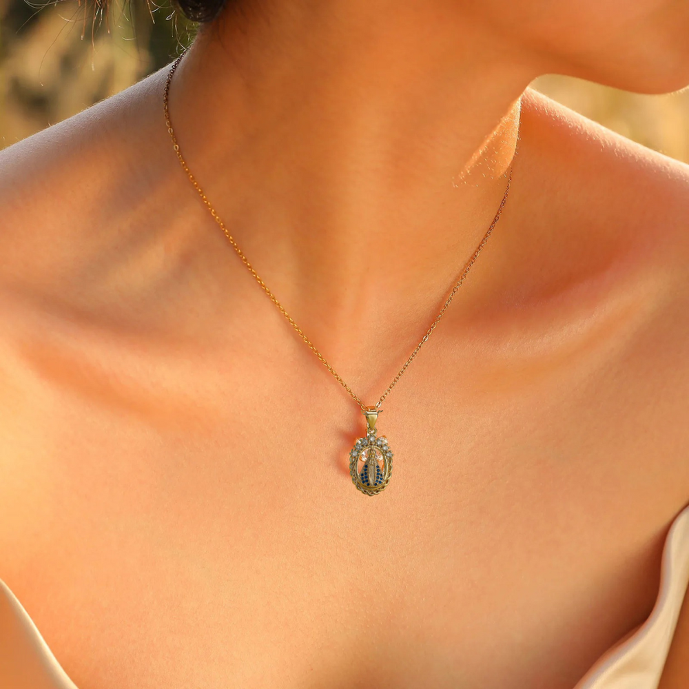 Gold necklace with a pendant on a person's neck against a blurred background