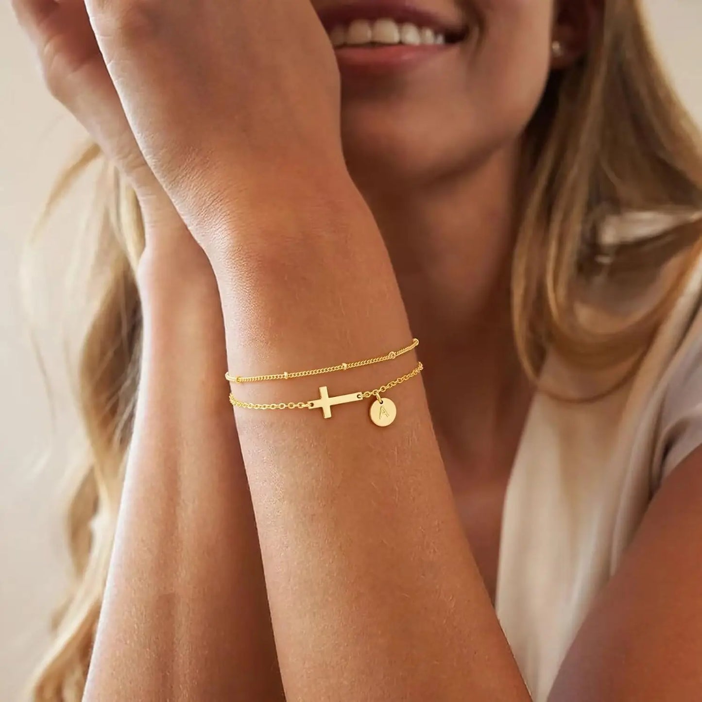 Woman wearing gold bracelets on a neutral background