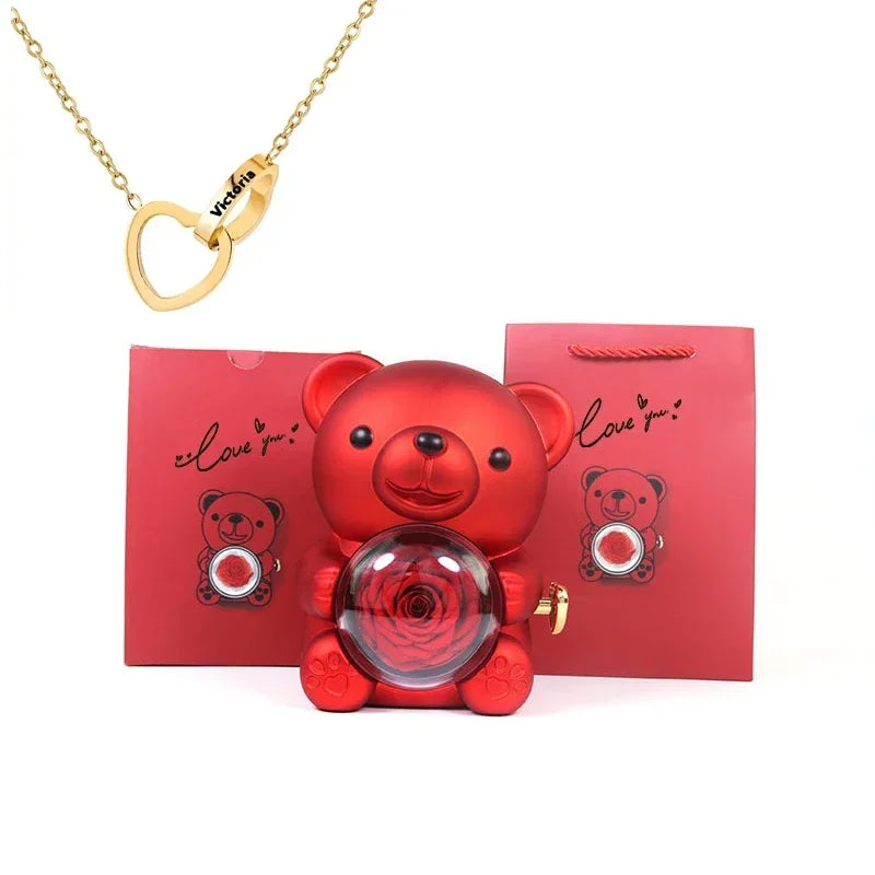 Red teddy bear-shaped perfume bottle with gold necklace and red packaging on a white background