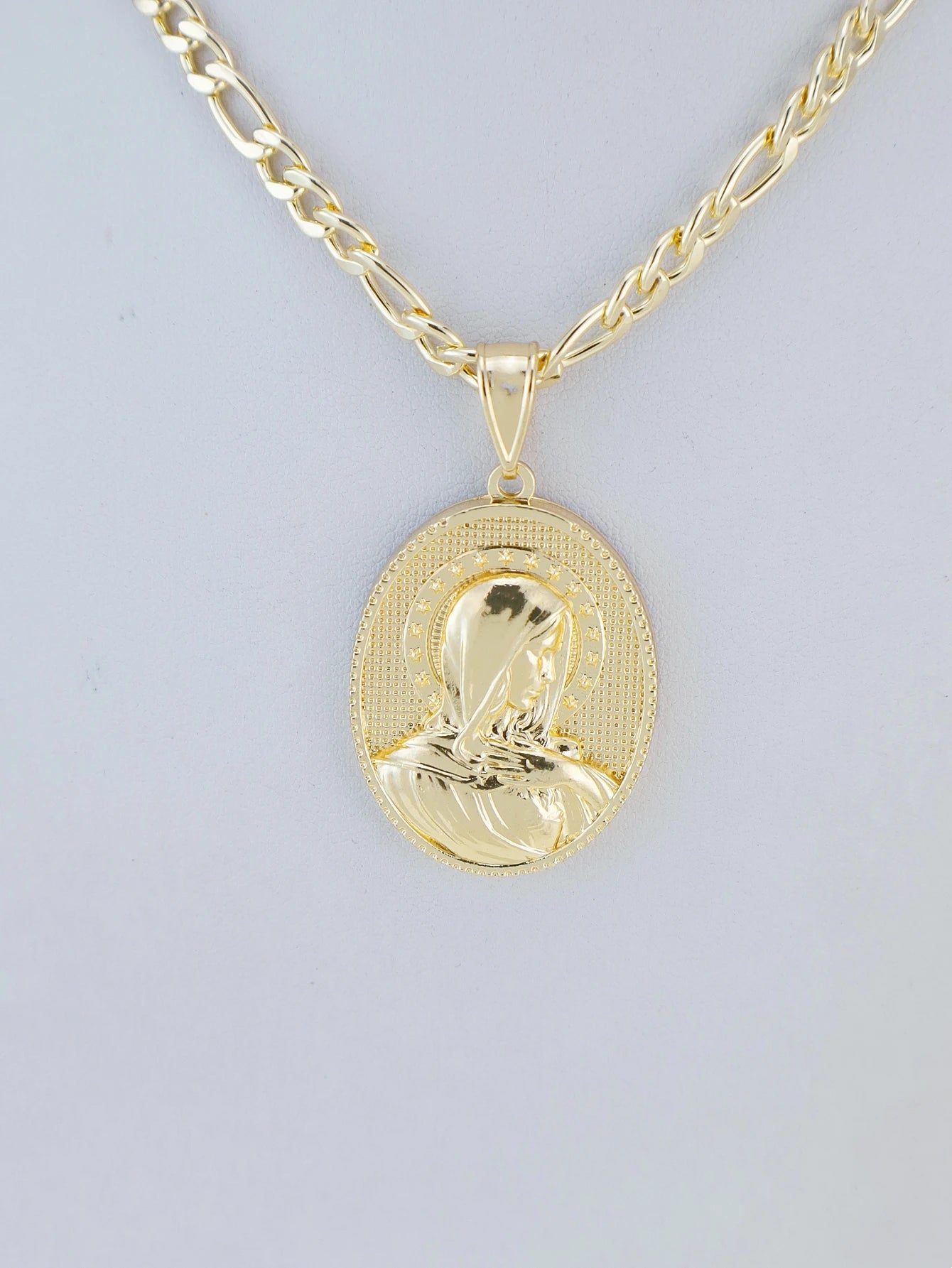 Gold necklace with a pendant on a light gray background