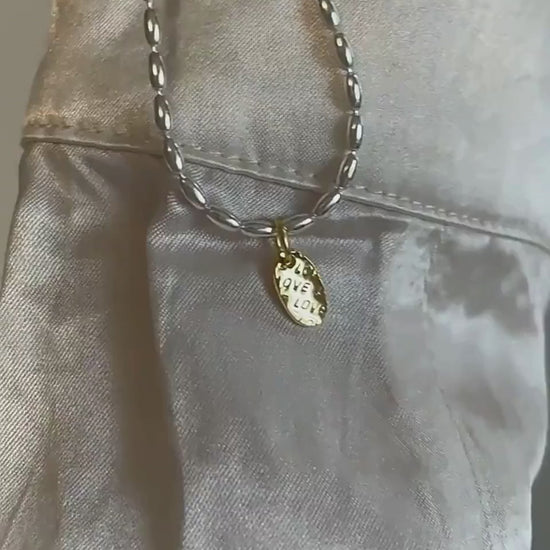 Video showing sterling silver necklace with gold drop charm in motion.