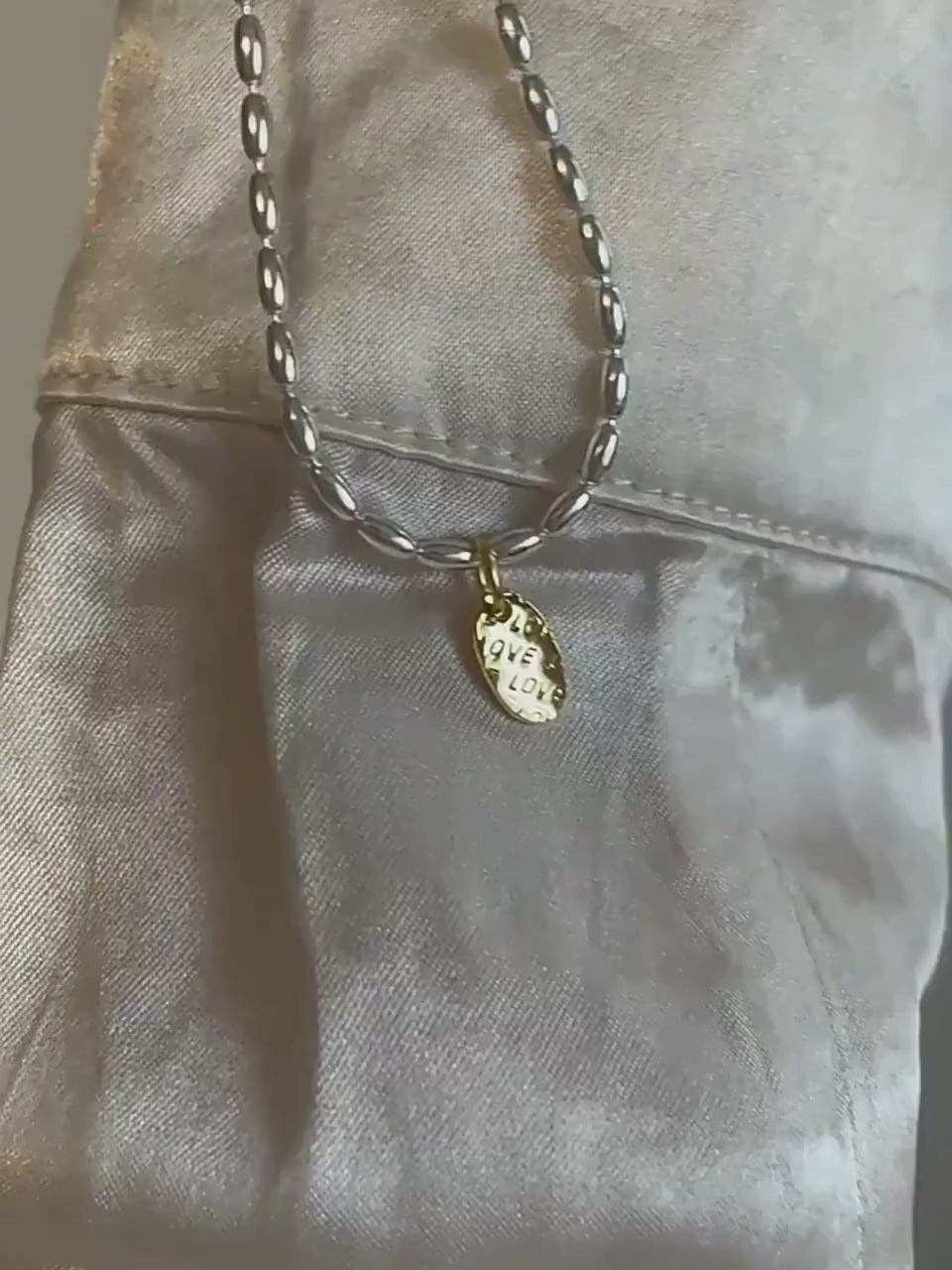 Video showing sterling silver necklace with gold drop charm in motion.