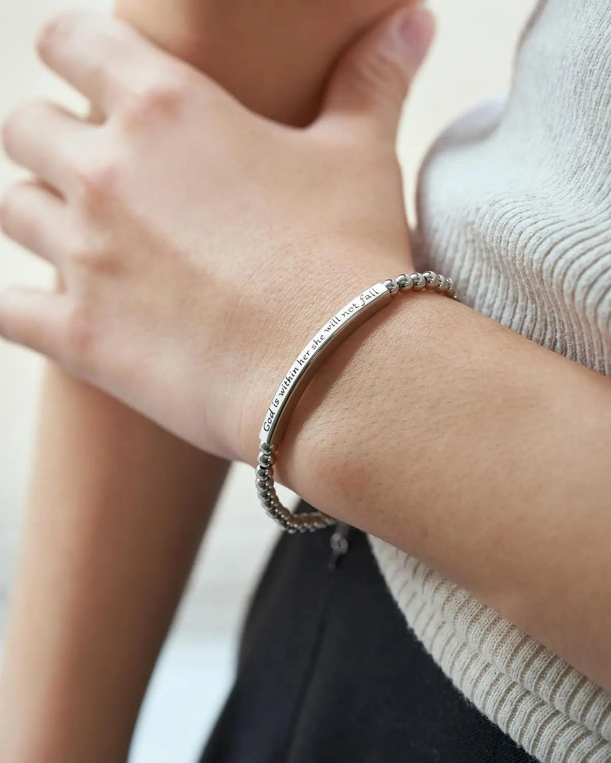 Close-up of a person wearing a silver bracelet on a blurred background