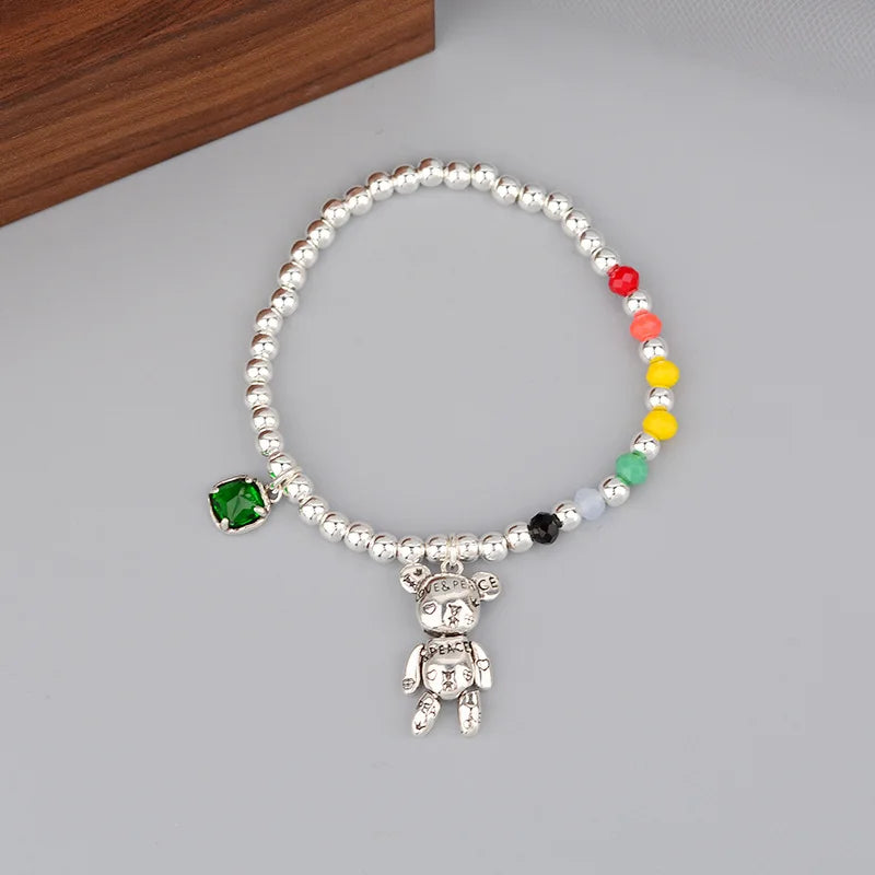 Bracelet with colorful beads and a teddy bear charm on a gray surface