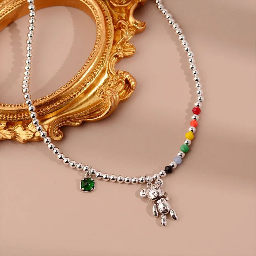 Necklace with colorful beads and a teddy bear charm on a beige background