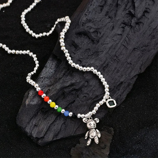 Necklace with colorful beads and a teddy bear charm on dark wood background