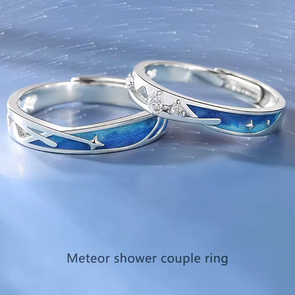 Two silver rings with star and moon designs on a blue background