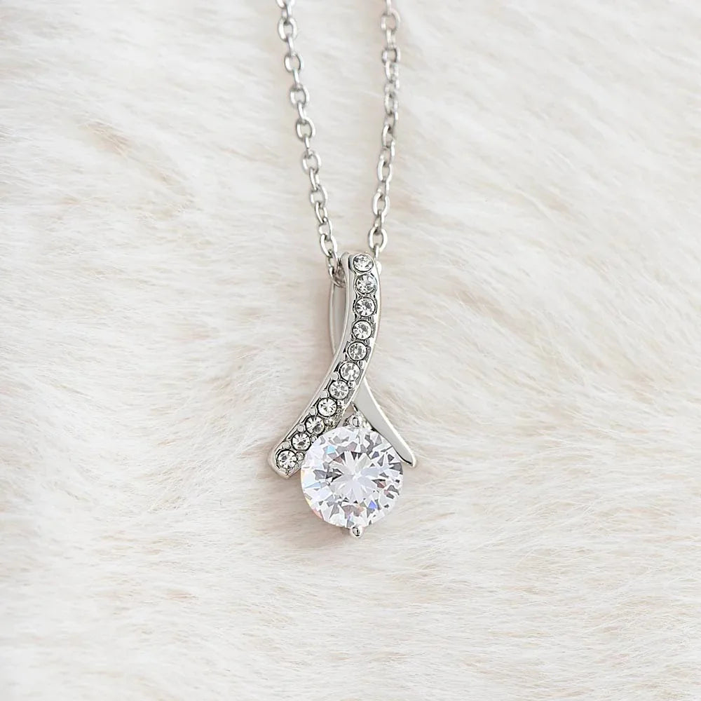 Silver necklace with a diamond pendant on a light wooden background