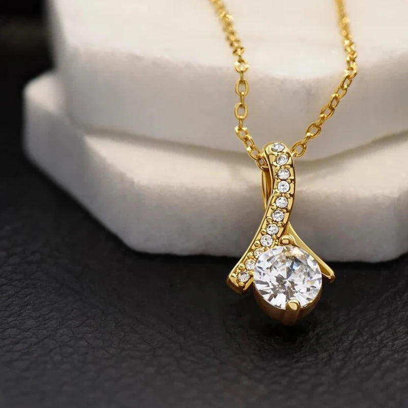 Gold necklace with a diamond pendant on a textured surface