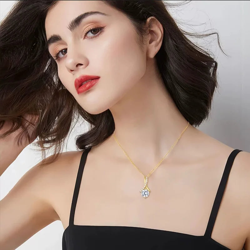 Woman wearing a gold necklace with a clear pendant against a neutral background