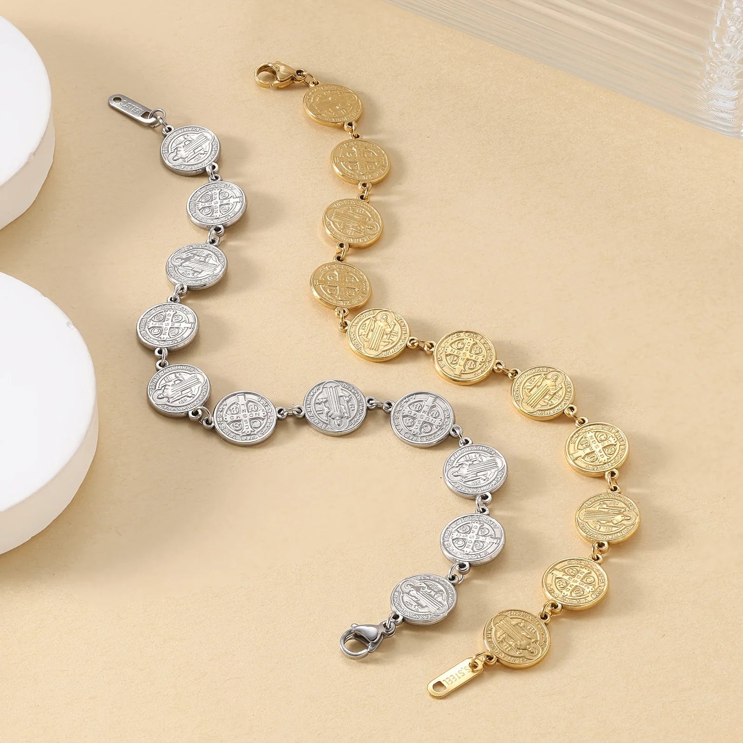 Two bracelets, one gold and one silver, on a beige surface.