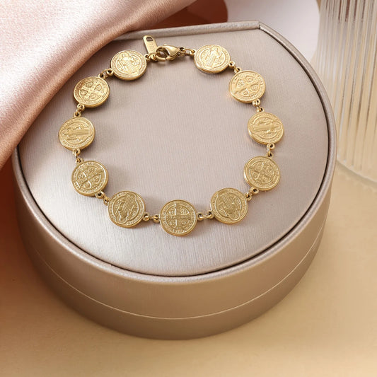 Gold bracelet with coin-like charms on a beige cushioned box