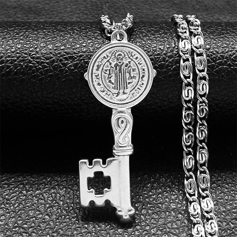 Silver key-shaped pendant with chain on a textured black surface