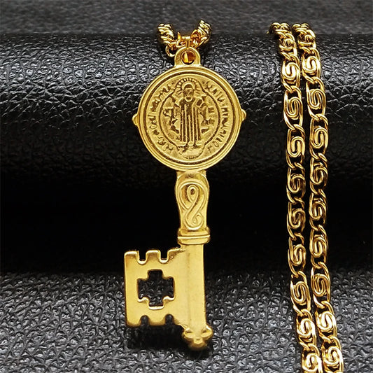 Gold key-shaped pendant with chain on a black textured background