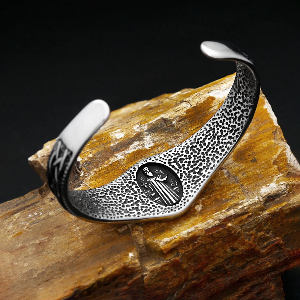 Silver bracelet with intricate design on a stone surface