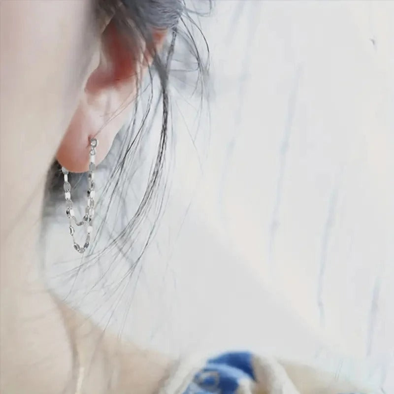 Close-up of an ear with a dangling earring on a blurred background