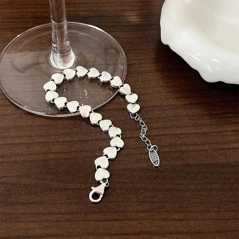 Silver bracelet with heart-shaped links on a wooden surface