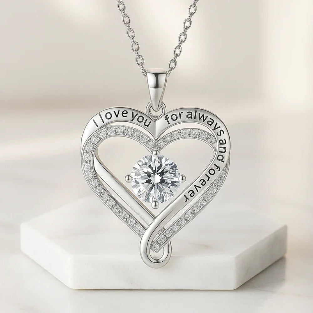 Heart-shaped silver necklace with diamond and engraved text on a light background