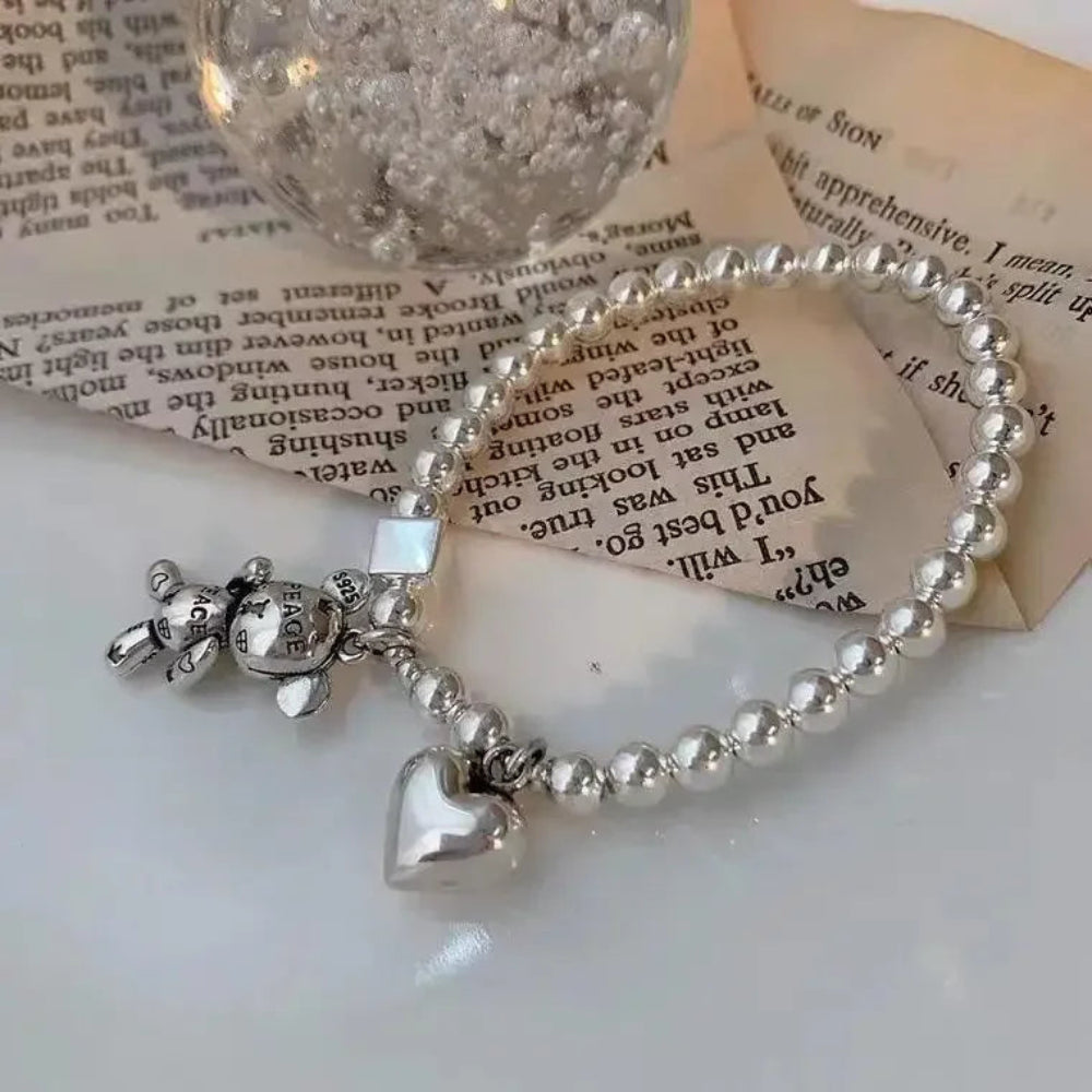 Silver bracelet with charms on a surface with text