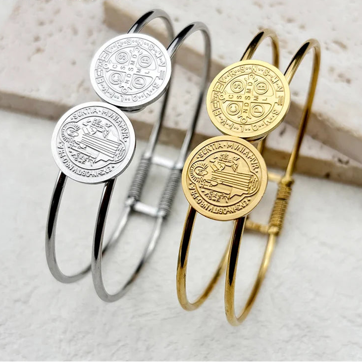 Two bangles in silver and gold with engraved designs on a light background
