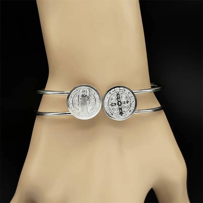 Silver bangle with circular designs on a mannequin arm against a black background