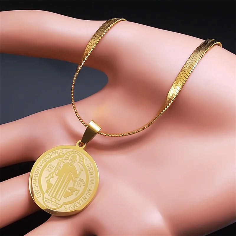 Gold necklace with a pendant on a hand against a dark background