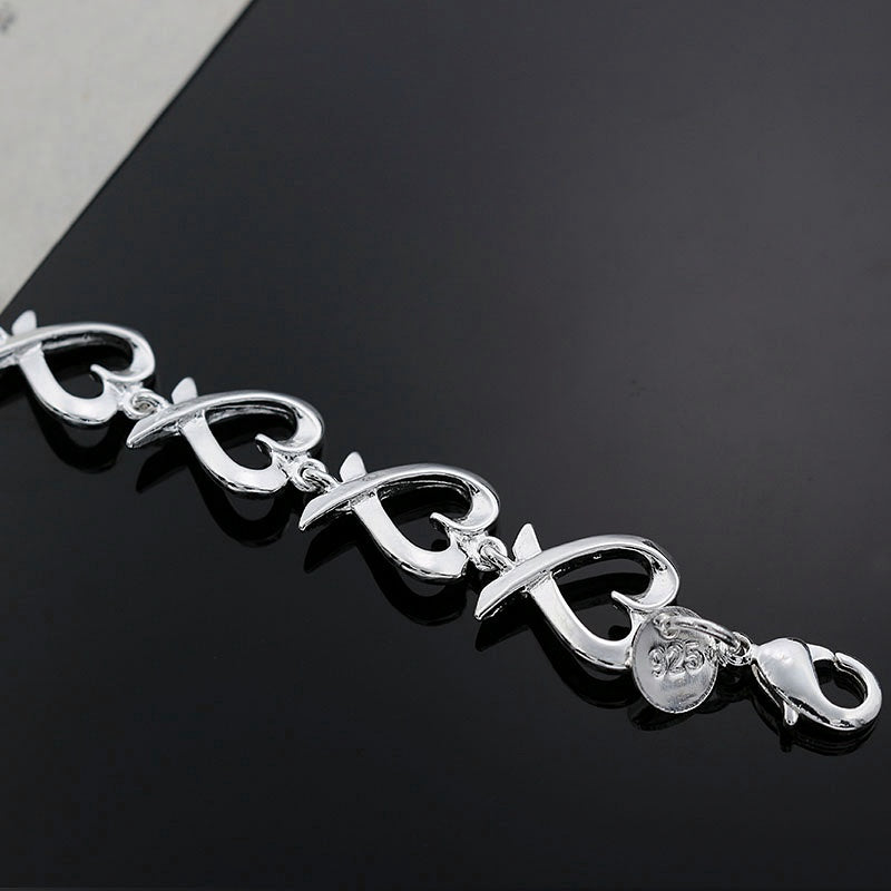 Silver bracelet with a heart charm on a black background