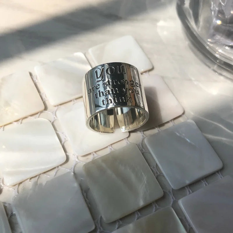 Silver ring with engraved text on a mosaic tile surface