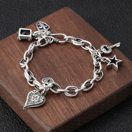 Silver charm bracelet on a wooden block with a dark background
