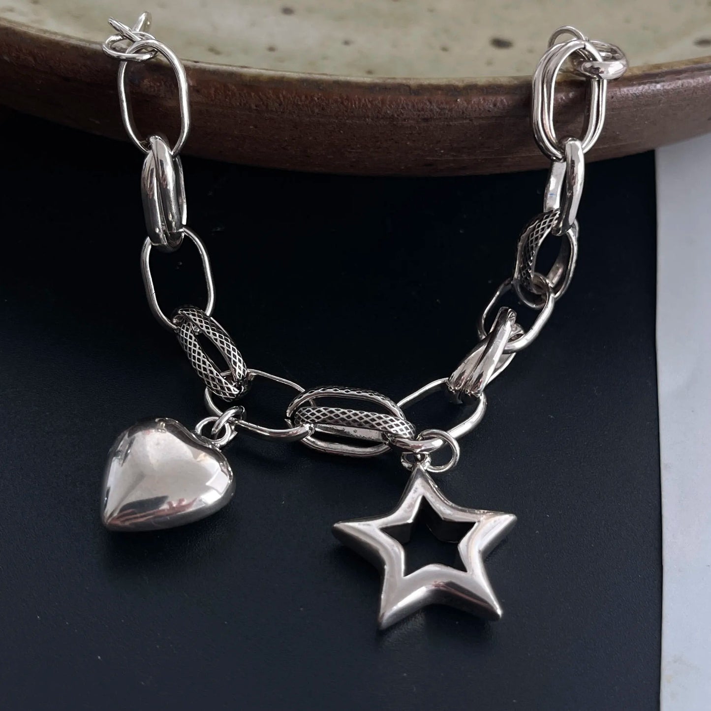 Silver bracelet with heart and star charms on a dark surface