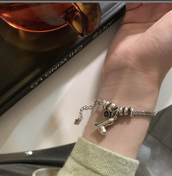 Silver bracelet with heart charm on wrist 