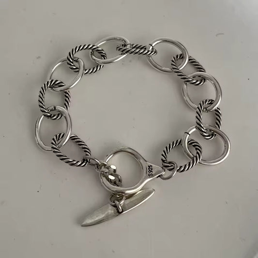 Silver chain bracelet with a charm on a light gray background