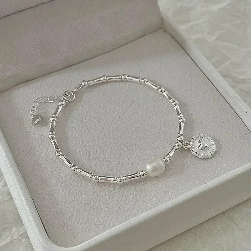 Silver bracelet with a pearl charm on a light gray surface
