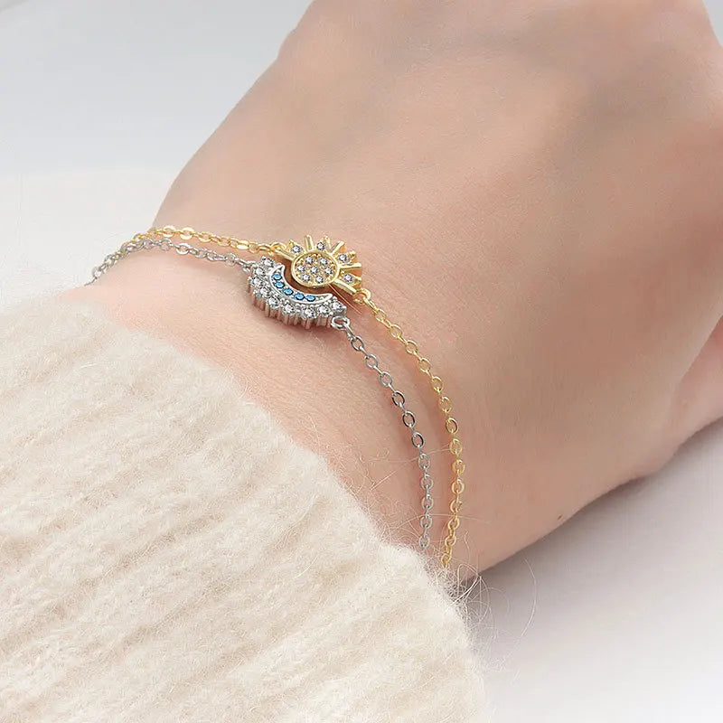 Close-up of a person's wrist wearing a delicate bracelet with a gold and silver chain on a light background.