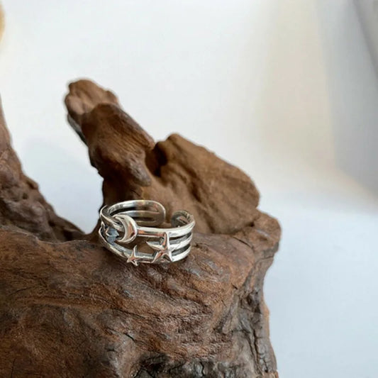 Silver ring with star and moon design on a piece of wood